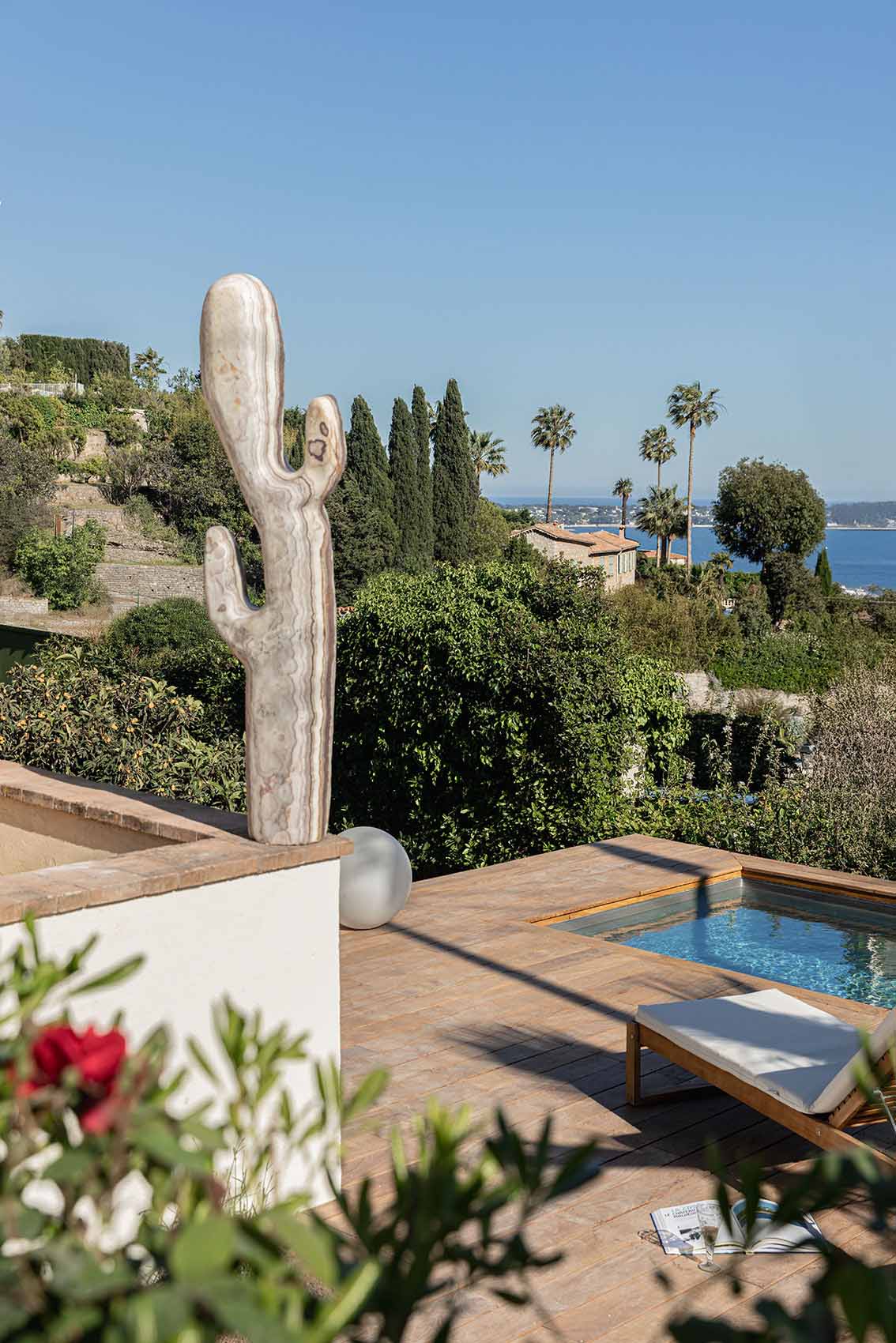 Veined marble cactus sculpture on the terrace, pool and bay panorama beyond