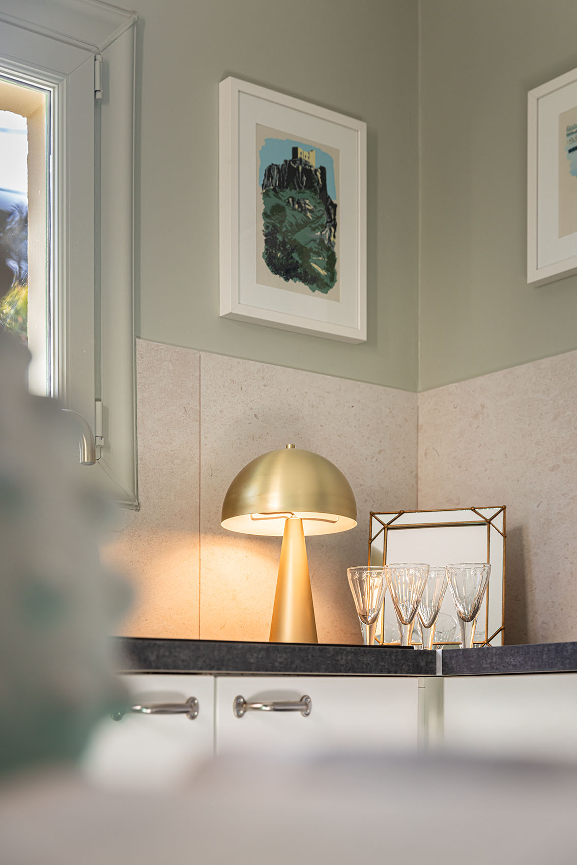 Kitchen corner with lit gold mushroom lamp, crystal glasses and framed watercolour print