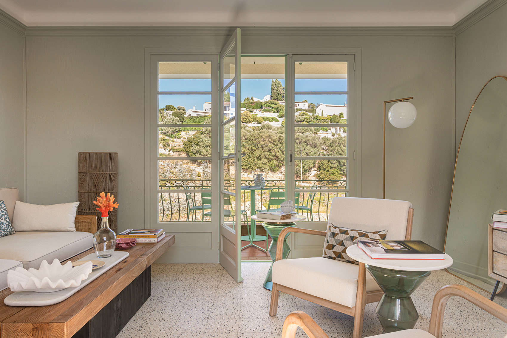 Main living room with wide-open French doors onto the balcony and olive hillside