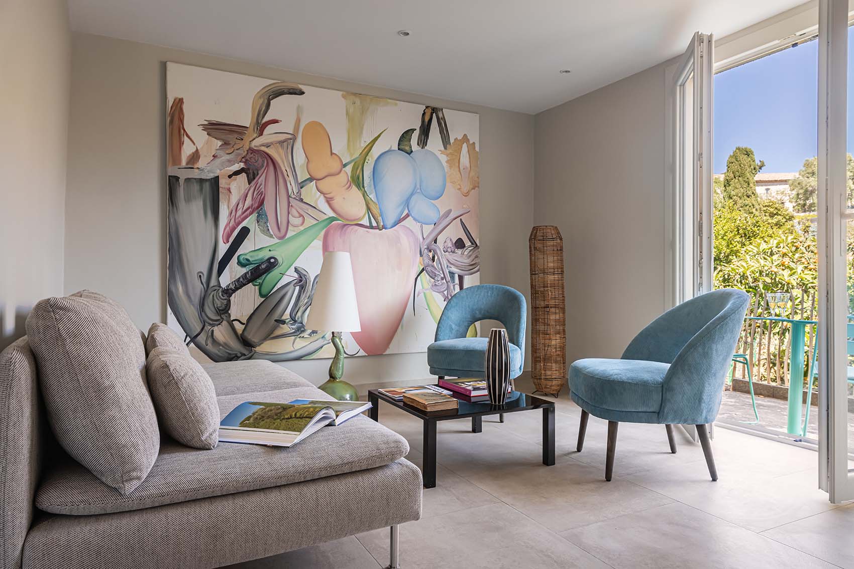Studio with large abstract botanical canvas, grey sofa, blue velvet armchairs and French doors
