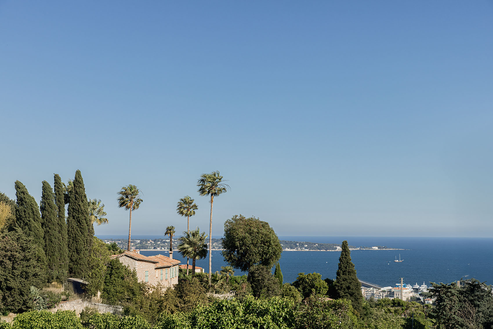Panoramic view over Provençal hills, cypress and palm trees, and the bay of Cannes