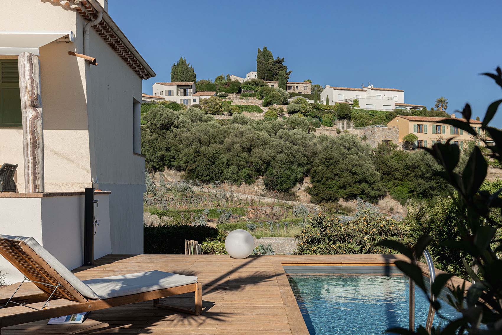 Wooden terrace, pool, sun lounger and Provençal village on the olive hillside
